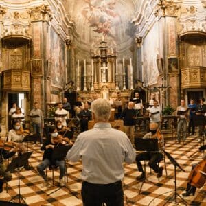 A conductor leading an orchestra in an music hall.