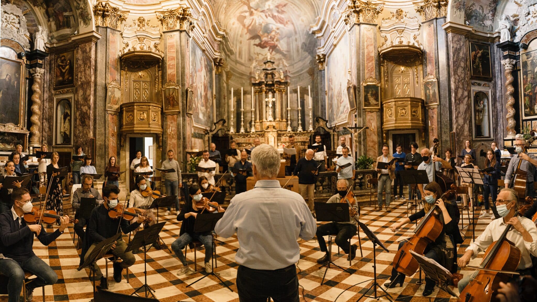 A conductor leading an orchestra in an music hall.