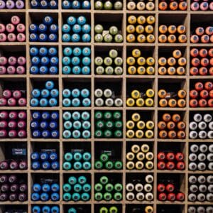 Different color spray paints organized in cubbies according to their color.