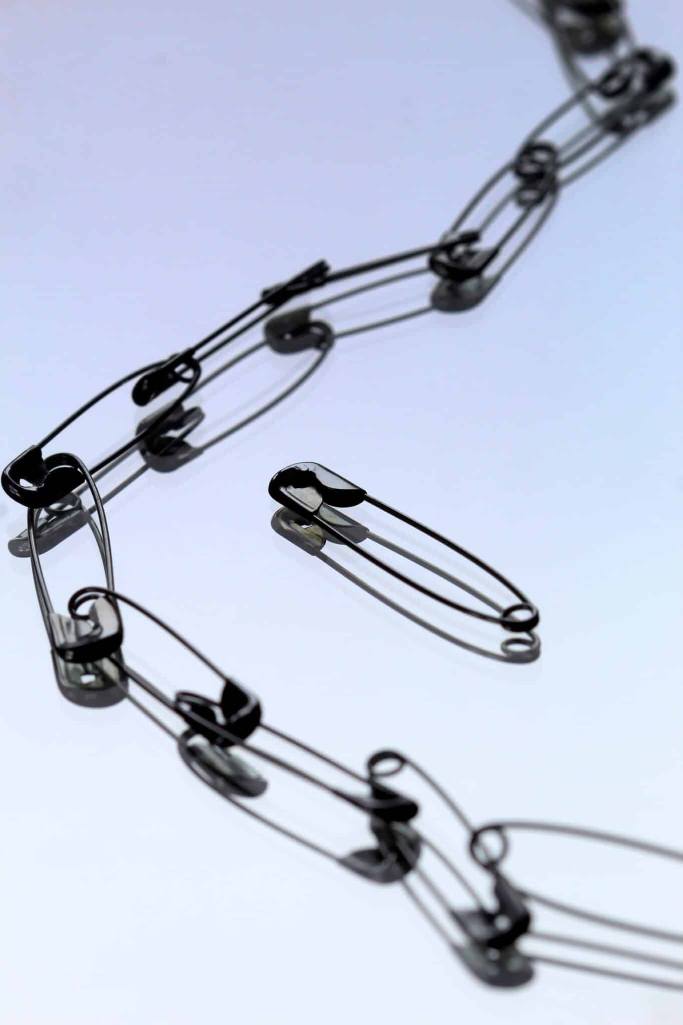 Safety pins clipped together in a chain, with one outside of the chain.