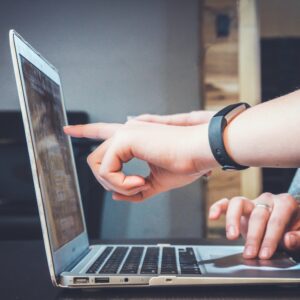 Two sets of hands pointing at a laoptop screen.