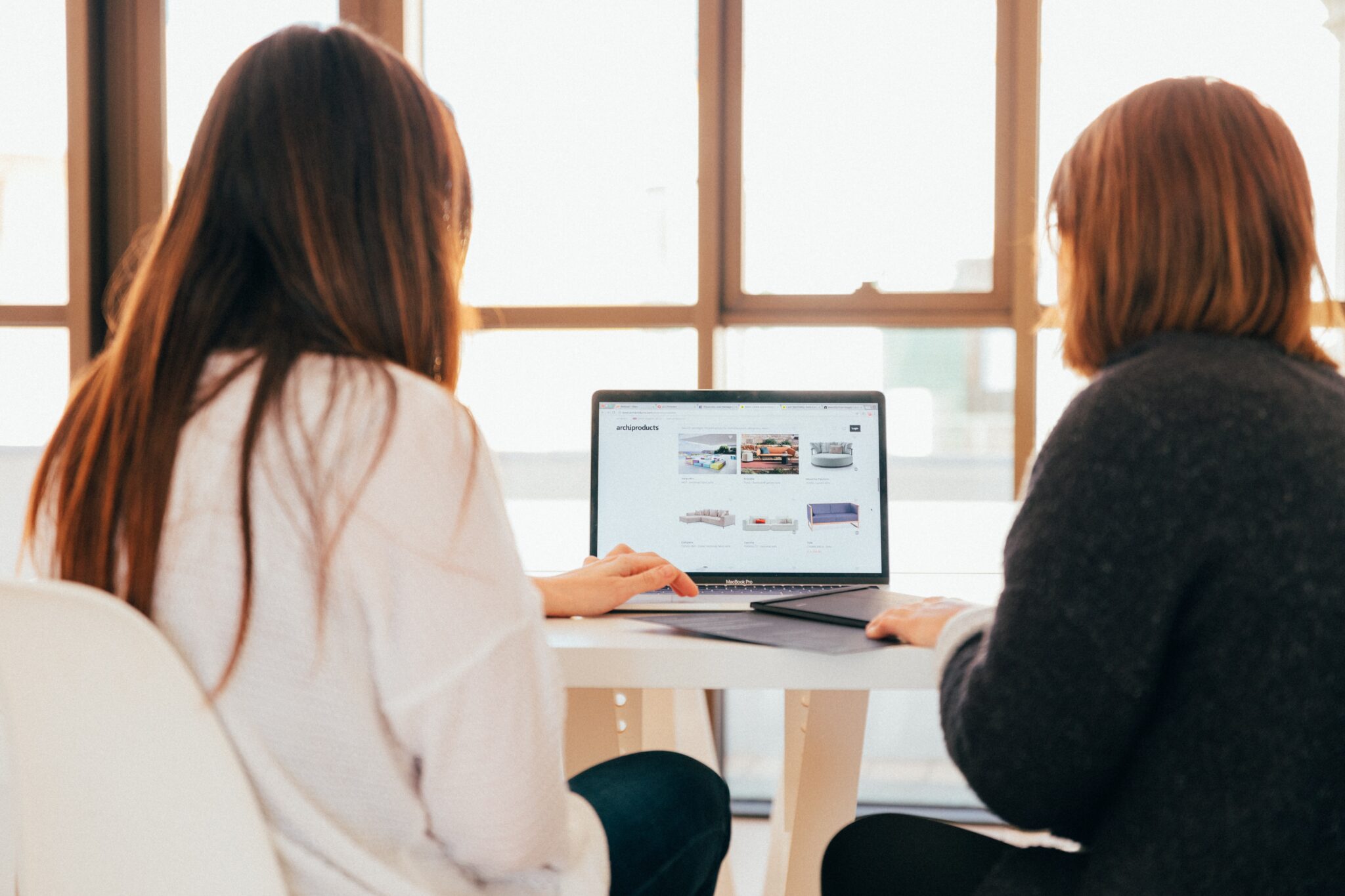 Two women in an office looking at a laptop screen with analytics on it.