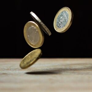 4 1 pound coins falling onto a wooden table.